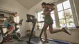 One person runs on the Peloton Tread at home and another cycles on a Peloton Bike 