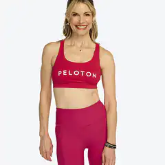 Headshot of Peloton instructor Kristin McGee. She's wearing a red two-piece Peloton workout outfit and smiling.