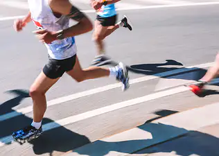 A close-up photo of runners' lower bodies quickly running a marathon.