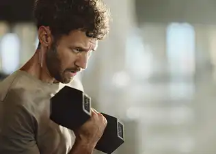 A man lifting a dumbbell. He is locked in to his workout.