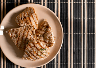 A plate of four grilled chicken breasts.