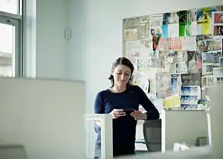 A woman standing in front of a vision board in her office.