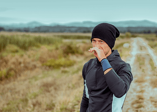 A man experiencing a runny nose when exercising outside.