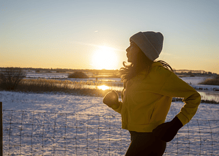 A woman exercising to ease seasonal affective disorder symptoms. She's going for a run in the early morning on a snowy day.