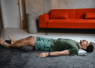 Man rests in Savasana, a restorative yoga pose