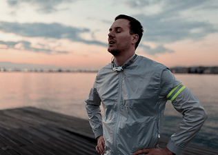 A man breathing and feeling happy after a long morning run outside.