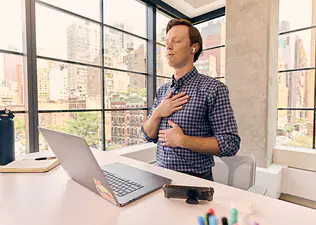 An office worker engaged in a mediation while sitting at a desk