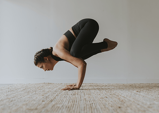 Woman practices Crow Pose, and advanced yoga pose