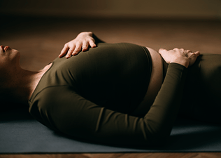 Photo of woman's torso as she reclines on the floow in Savasana yoga pose 