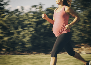 Woman running while pregnant outside 