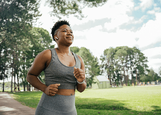 A person running on a sunny warm day in a park.