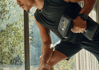 Man rowing a dumbbell during a Peloton strength training workout.