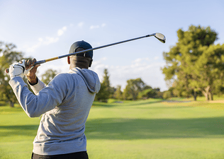 Man swinging golf club on course