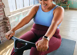 Woman smiling while doing a rowing machine workout on the Peloton Row
