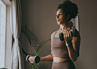 Woman does arm exercises with light weights at home