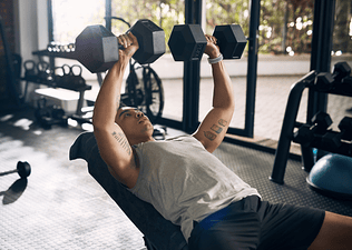 Man performs an incline dumbbell chest press on bench at gym 