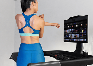 Woman in Peloton Apparel stretching while standing on the Peloton Cross Training Series Tread+