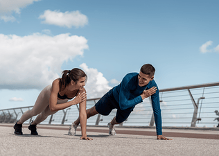 Woman and man do shoulder taps exercise outdoors
