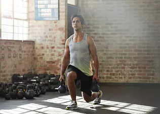 Man doing weighted lunge in gym