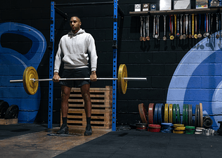 Man in a gym holding a loaded barbell about to perform bent-over barbell rows with proper form