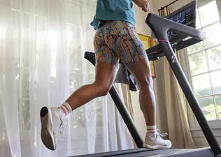 Woman runs on Peloton Tread at home