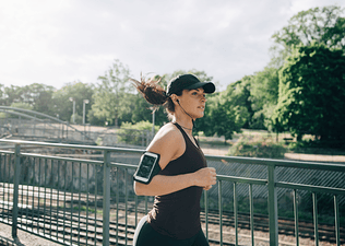 Woman jogging outside with black baseball cap and black tank top