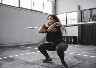 Woman does a squat with a barbell bar without weights, a beginner barbell exercise