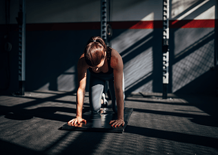 Woman preparing to do a bear plank core exercise during a workout at the gym.