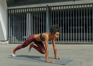Woman outdoors performs mountain climbers exercise