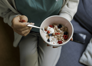 A person eating a Greek yogurt parfait as a healthy late-night snack,