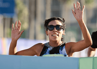 Woman crossing the finish line of a race after setting a running goal.