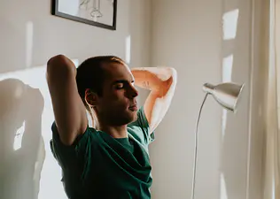 A man doing spinal mobility exercises while sitting at his desk at home.