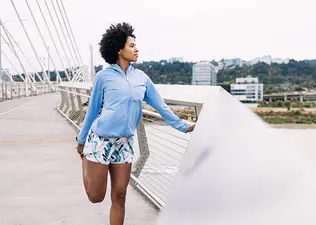 Woman outdoors does a quad stretch