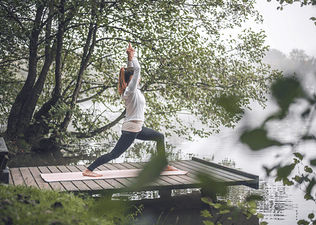 Woman doing Warrior One Yoga Pose in Woods