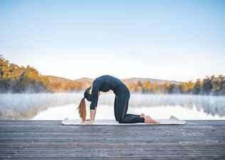 Woman practices Cat Cow yoga pose outdoors