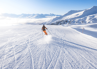 Person skis on a snowy ski slope 