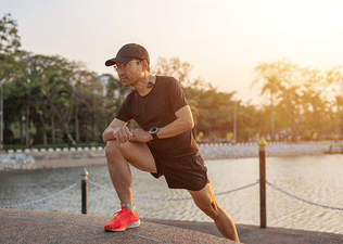 Man stretching outside in morning sunlight as part of marathon strength training