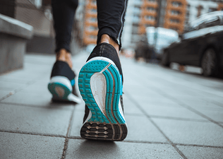 A close-up behind view of a woman's shoes as she runs with plantar fasciitis.