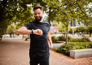 Man checking watch while running outside