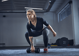 Woman doing a dumbbell snatch exercise 