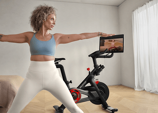 Woman doing a yoga cross training workout at home with her Peloton Bike.