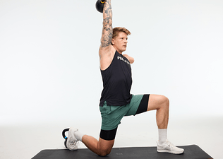 Peloton instructor Logan Aldridge kneeling with a kettlebell pressed overhead