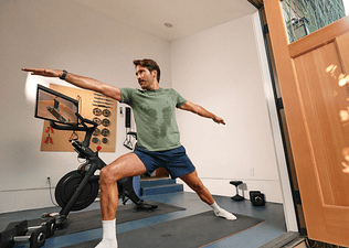 Man exercising next to a Peloton Bike+