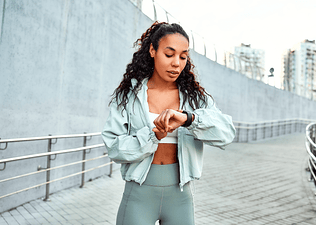 A woman in workout clothes checking her heart rate variability with the help of a smartwatch.