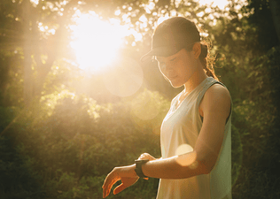 Woman looking at her smartwatch in a park while running in the morning 