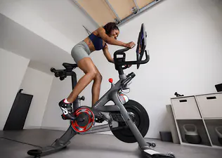 Woman doing bike sprints on a Peloton Bike during a home cycling workout.