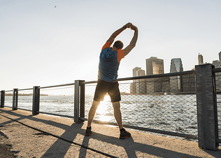 Man does an overhead reach lat stretch outdoors