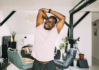 Man at home doing standing stretches to loosen up during the work day.