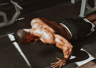 Man doing bodyweight back exercises in a gym.