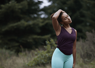 Woman stretches neck outdoors 